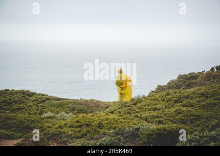 Wandern bei starkem Regen und Tragen einer Regenjacke entlang des Fisherman Trail im südlichen Teil Portugals bei Regenwetter auf dem Weg nach Cape St. Vic Stockfoto