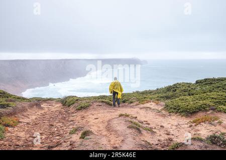 Wandern bei starkem Regen und Tragen einer Regenjacke entlang des Fisherman Trail im südlichen Teil Portugals bei Regenwetter auf dem Weg nach Cape St. Vic Stockfoto