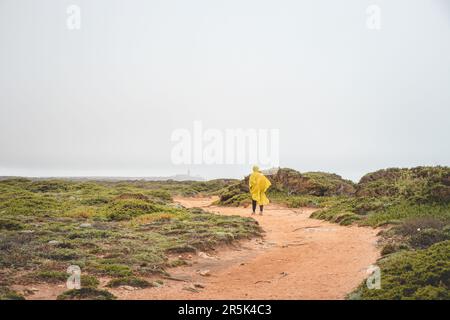 Wandern bei starkem Regen und Tragen einer Regenjacke entlang des Fisherman Trail im südlichen Teil Portugals bei Regenwetter auf dem Weg nach Cape St. Vic Stockfoto