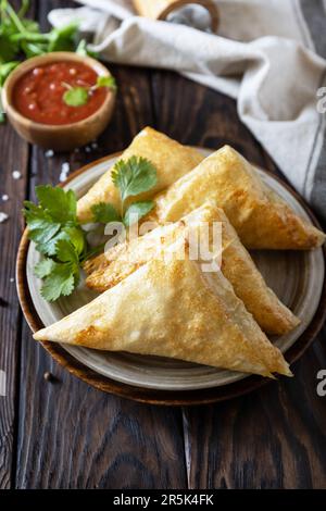 Asiatisches Essen. Vegetarische samsa (Samosas) mit Tomatensoße auf einem Holztisch. Beliebt in Indonesien als Risoles Sayur. Stockfoto