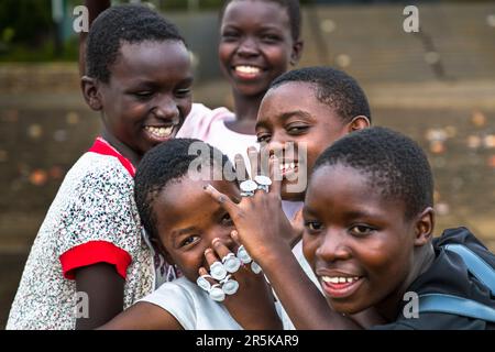 Junge Mädchen sammeln die Mützenringe der maheu-Packs, die zu Ehren von Malawis erstem Präsidenten (Hastings Kamuzu Banda) an den Nationalfeiertagen weggeworfen wurden, um Schmuck herzustellen. Maheu oder Mahewu ist ein typisches Getränk in Malawi, das aus fermentiertem Mais hergestellt wird. Lilongwe, Malawi Stockfoto