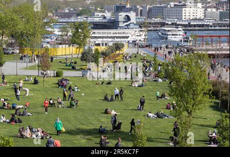 . Ein Sonntag am Goldenen Horn in Istanbul. Die Leute sonnen sich und entspannen sich auf dem Rasen. Istanbul, Karakoy Türkei - 2023. Mai Stockfoto