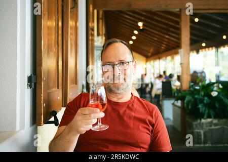 Porträt eines Mannes mittleren Alters im Restaurant, der ein Glas Wein hält Stockfoto