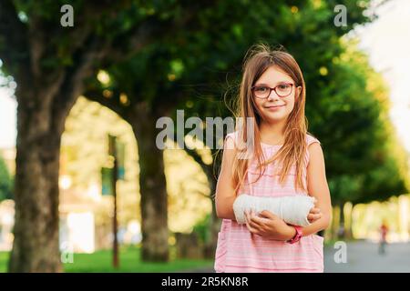 Außenporträt eines süßen kleinen Mädchens mit Gips Stockfoto