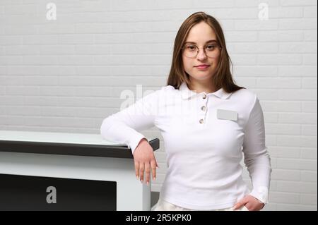 Porträt einer weiblichen Rezeptionistin vor dem Rezeptionstresen in Ambulanz, Klinik oder Kursalon. Stockfoto