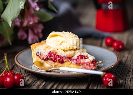 Torte mit saurer Kirschcreme, Creme Patisserie und Krümeln, serviert mit Vanilleeis. Rustikale und stimmungsvolle Atmosphäre und Dekoration. Stockfoto