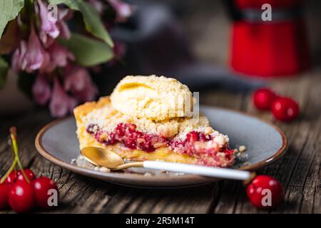 Torte mit saurer Kirschcreme, Creme Patisserie und Krümeln, serviert mit Vanilleeis. Rustikale und stimmungsvolle Atmosphäre und Dekoration. Stockfoto