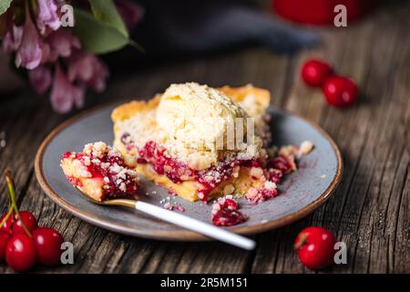 Torte mit saurer Kirschcreme, Creme Patisserie und Krümeln, serviert mit Vanilleeis. Rustikale und stimmungsvolle Atmosphäre und Dekoration. Stockfoto