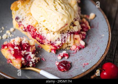 Torte mit saurer Kirschcreme, Creme Patisserie und Krümeln, serviert mit Vanilleeis. Rustikale und stimmungsvolle Atmosphäre und Dekoration. Stockfoto