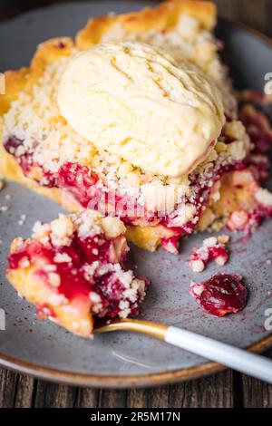 Torte mit saurer Kirschcreme, Creme Patisserie und Krümeln, serviert mit Vanilleeis. Rustikale und stimmungsvolle Atmosphäre und Dekoration. Stockfoto