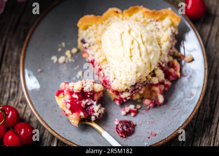 Torte mit saurer Kirschcreme, Creme Patisserie und Krümeln, serviert mit Vanilleeis. Rustikale und stimmungsvolle Atmosphäre und Dekoration. Stockfoto