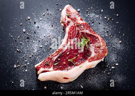 Roher Schnitt von Premiumsteak mit Knochen. Rumpsteak mit Marmor, trocken gereift, auf schwarzem Hintergrund. Frisches Ribeye Steak. Stockfoto