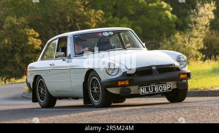 Stony Stratford, Großbritannien - Juni 4. 2023: 1976 weißer MG B GT klassischer Sportwagen, der auf einer englischen Landstraße fährt. Stockfoto