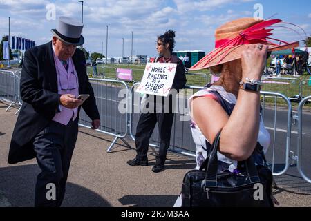 Epsom, 3. Juni 2023. Rennfahrer passieren am Tag des Epsom Derby einen Tierschützer, der vor der Rennbahn Epsom Downs ein Schild hält. Aktivisten von Gruppen wie Animal Rising und Animal Aid betrachten Pferderennen als grausame und ausbeuterische Industrie. £150.000 wurden für zusätzliche Sicherheitsmaßnahmen für das Epsom Derby ausgegeben. Die Polizei von Surrey berichtete, dass 31 Verhaftungen vorgenommen wurden, einschließlich 19 präventiven Verhaftungen. Kredit: Mark Kerrison/Alamy Live News Stockfoto