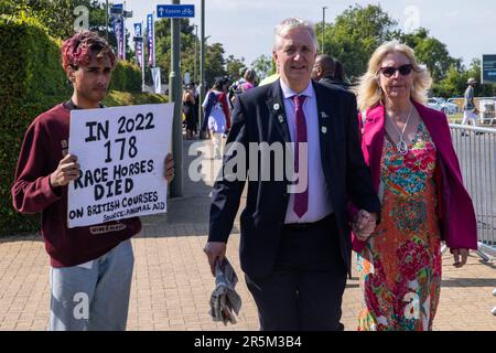 Epsom, Großbritannien. 3. Juni 2023. Rennfahrer passieren am Tag des Epsom Derby einen Tierschützer, der vor der Rennbahn Epsom Downs ein Schild hält. Aktivisten von Gruppen wie Animal Rising und Animal Aid betrachten Pferderennen als grausame und ausbeuterische Industrie. £150.000 wurden für zusätzliche Sicherheitsmaßnahmen für das Epsom Derby ausgegeben. Die Polizei von Surrey berichtete, dass 31 Verhaftungen vorgenommen wurden, einschließlich 19 präventiven Verhaftungen. Kredit: Mark Kerrison/Alamy Live News Stockfoto