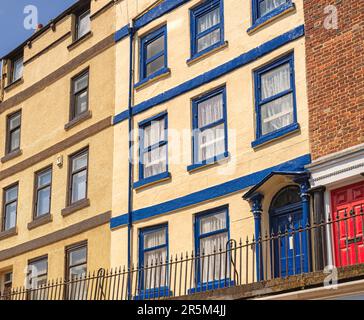 Stadthäuser in verschiedenen Farben auf einem Hügel. Ein rotes Backsteingebäude befindet sich im Vordergrund und die anderen sind weiß getüncht. Stockfoto