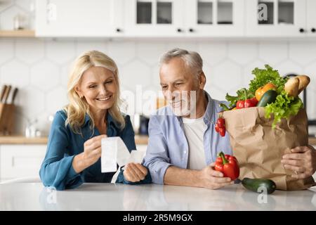 Glückliche Seniorenpartner In Der Küche, Die Rechnungen Nach Der Lieferung Prüfen Stockfoto