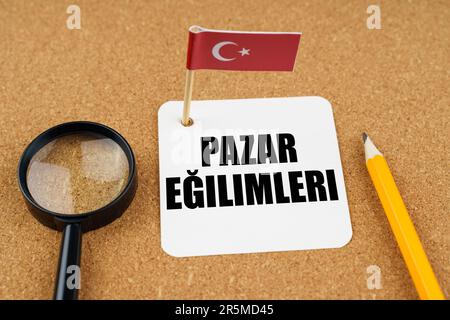 Auf dem Tisch liegt die Flagge der Türkei, ein Bleistift, eine Lupe und ein Blatt Papier mit einer Inschrift in Türkisch, übersetzt in Englisch - Markt Stockfoto