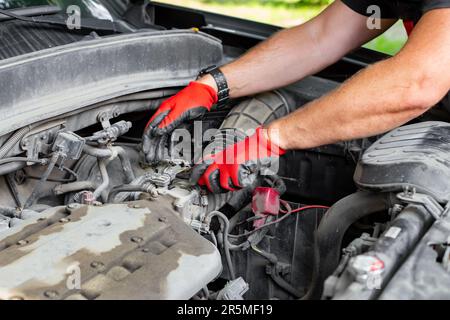 Autoreparaturen. Der Automechaniker trennt die Luftleitung vom Fahrzeugmotor. Stockfoto