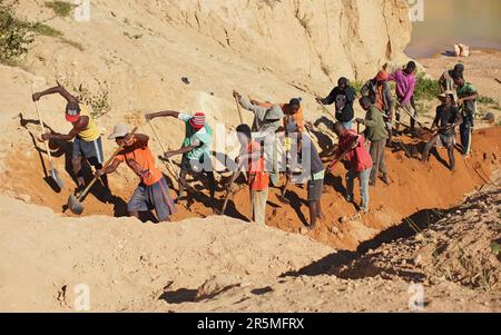 Ilakaka, Madagaskar - 30. April 2019: Gruppe unbekannter madagassischer Männer, die Saphir im Tagebau abbauen, indem sie an einem sonnigen Tag den Boden mit Schaufeln bewegen. Thi Stockfoto