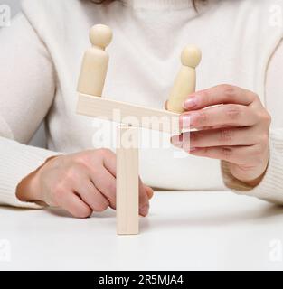 Zwei hölzerne Figuren eines Mannes stehen einander gegenüber, das Konzept der Versöhnung der Gegner, das Ende des Mobbing, die Suche nach einem Kompromiss Stockfoto