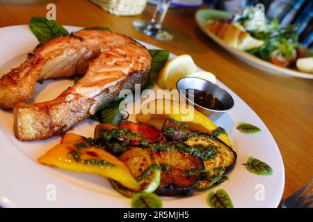 Gegrillter Lachs mit Gemüse, Zitrone und Pesto-Sauce. Das Gericht servieren. Geringe Schärfentiefe Stockfoto