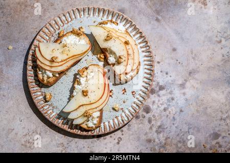 Bruschetta mit Birne, Ziegenkäse-Aufstrich, Nüssen und Honig Stockfoto