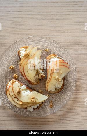 Bruschetta mit Birne, Ziegenkäse-Aufstrich, Nüssen und Honig Stockfoto