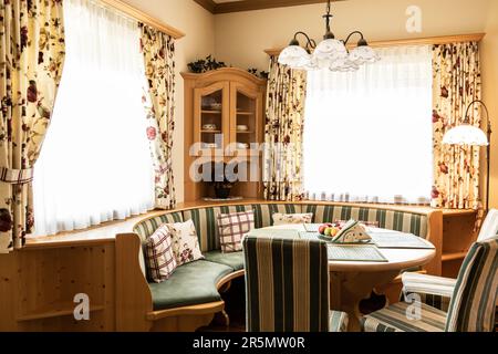 Esszimmerecke mit Holzmöbeln und großen Fenstern mit Sonnenlicht Stockfoto