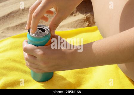 Frau öffnet Aluminiumdose mit Getränk auf gelber Decke, Nahaufnahme Stockfoto