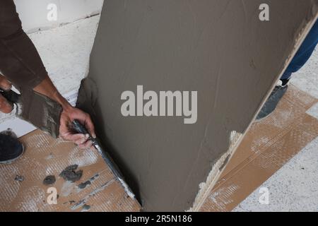 Arbeiter, die Zement auf Fliesen in Innenräumen anwenden, schließen Stockfoto