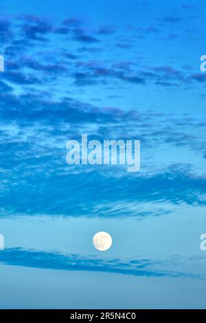 Vollmond und Wolken in der Dämmerung. Ein Vollmond erhebt sich in den Wolken. Stockfoto