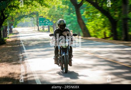 Männlicher Motorradfahrer, der mit hoher Geschwindigkeit auf der Straße fährt. Motorradfahrer mit voller Geschwindigkeit auf der Autobahn Stockfoto