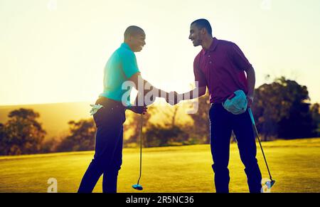 Möge der Kurs bei dir sein. Zwei Golfspieler schütteln sich die Hand auf dem Golfplatz. Stockfoto