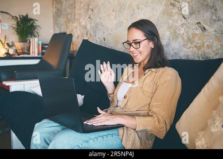 Die Welten waren getrennt, aber ich finde einen Weg. Eine junge Frau, die ein Notebook benutzt, um zu Hause auf dem Sofa ein Videogespräch zu führen. Stockfoto