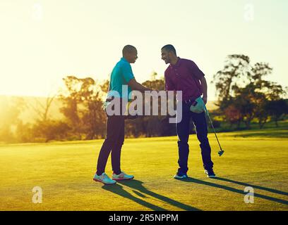Selbstvertrauen ist der wichtigste Faktor in diesem Spiel. Zwei Golfspieler schütteln sich die Hand auf dem Golfplatz. Stockfoto