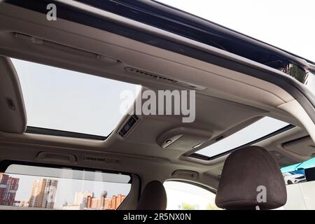 Blick auf die Decke des Autos mit einer durchsichtigen Doppelglasluke zur Belüftung, die sich so öffnen lässt, dass Sie den Himmel und die Wolken in der grauen Kabine von t sehen können Stockfoto