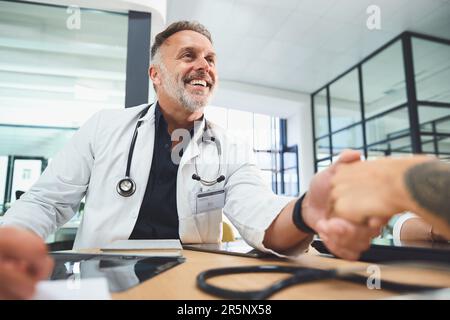 Wir wollen unseren Patienten die bestmögliche Versorgung bieten, die sie benötigen. Ärzte, die sich während einer Sitzung im Krankenhaus die Hände schütteln. Stockfoto