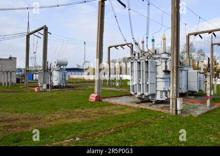 Große Umspannstation für industrielle Eisenmetalltransformatoren mit Transformatoren und Hochspannungselektrik sowie Drähten mit Überspannungsableitern zur Versorgung der Anlage Stockfoto