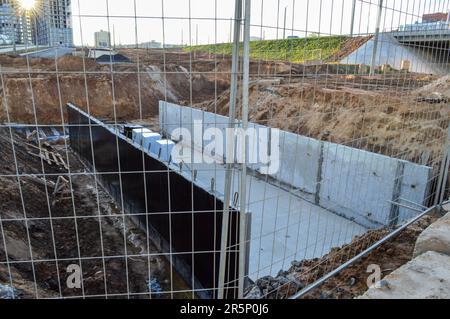 Dichtes und grobes Netz aus Metall auf der Baustelle. Einzäunung besonders gefährlicher Baustellen vor Besuchern. Hinter dem Raster ist ein Sand Stockfoto