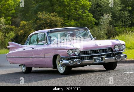 Stony Stratford, Großbritannien - 4. 2023. Juni: 1959 rosa CADILLAC-Klassiker, der auf einer englischen Landstraße fährt. Stockfoto
