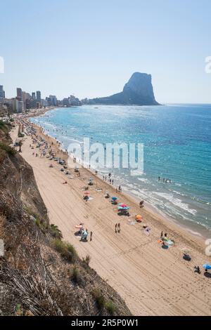 Calpe, Spanien - 19. Juli 2021: Sonniger Strand mit Touristen für Urlaub entlang der Küste von Calpe mit Blick auf die Felsformation 'ifach' Stockfoto