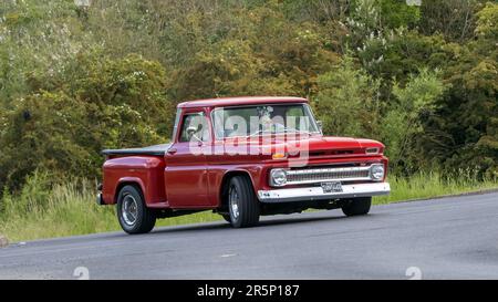 Stony Stratford, Großbritannien - 4. 2023. Juni: 1966 Uhr roter CHEVROLET C10 UHR ABHOLUNG in einem klassischen Auto, das auf einer englischen Landstraße fährt. Stockfoto