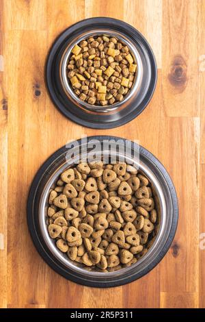 Trockenes Kibble-Tierfutter. Hunde- oder Katzenfutter in der Schüssel auf dem Holztisch. Draufsicht. Stockfoto
