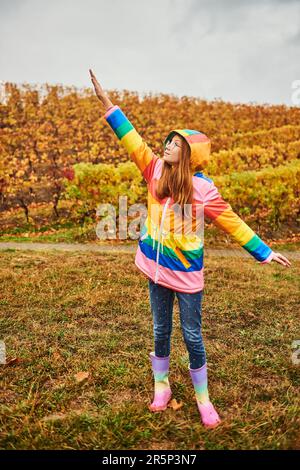 Außenporträt eines hübschen jungen Mädchens mit farbenfrohem Regenmantel Stockfoto