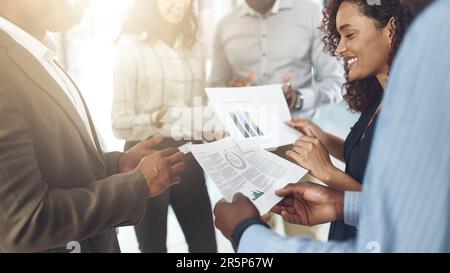 Wege finden, um ihre Profite auf dem Vormarsch zu halten. Nahaufnahme einer Gruppe von Geschäftsleuten, die Papierkram in einem Büro durchgehen. Stockfoto