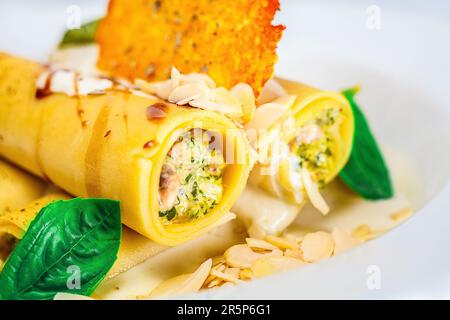 Eine farbenfrohe Platte mit frisch gekochten Gemüse-Cannelonni mit Mandel und Basilikum, eine perfekte Kombination für gesunde Ernährung und Wohlbefinden. Stockfoto
