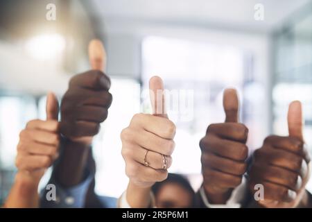 Erstaunliche Dinge kommen auf Sie zu. Nahaufnahme einer Gruppe von Geschäftsleuten, die in einem Büro Daumen nach oben zeigen. Stockfoto