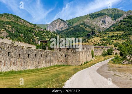 Blick auf die schmale Straße entlang der alten Militärfestung als Berge unter blauem Himmel im Hintergrund in Vinadio, Italien. Stockfoto