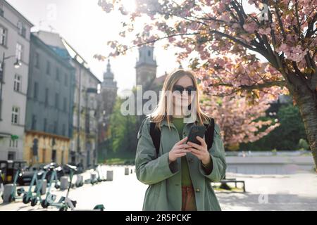 Schöne, stilvolle Kleidung Blondes Mädchen Tourist reist auf der Suche nach Wegbeschreibungen auf dem Smartphone durch die Altstadt von Krakau in der Nähe des Wawel Stockfoto